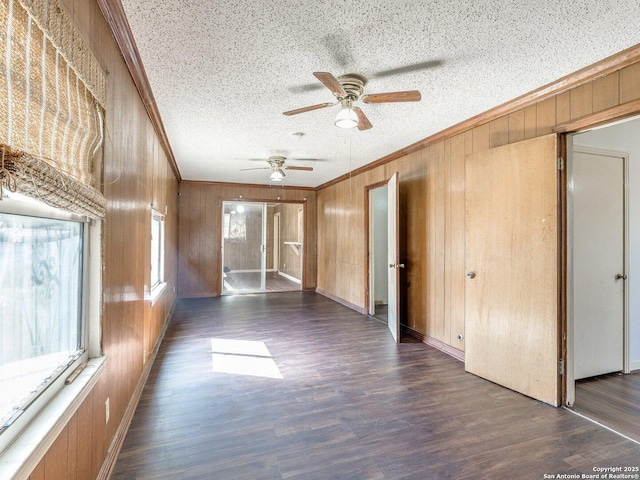 empty room with ornamental molding, wooden walls, dark hardwood / wood-style flooring, and a textured ceiling