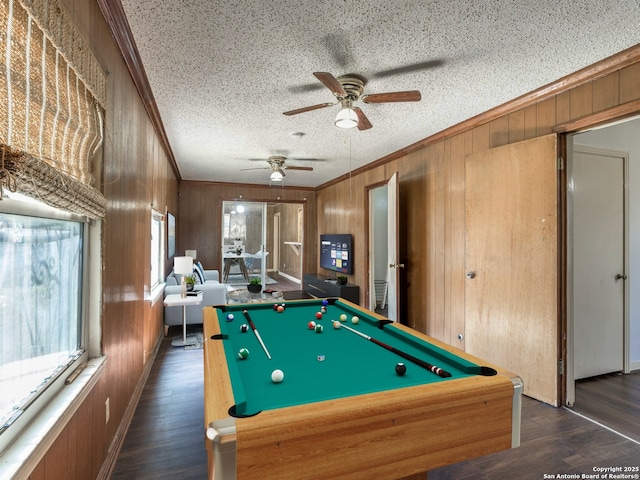 playroom with dark wood-type flooring, crown molding, pool table, a textured ceiling, and wooden walls