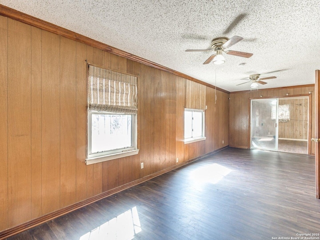 spare room featuring dark wood-type flooring, ornamental molding, and a textured ceiling