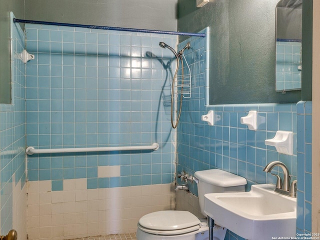 bathroom with sink, a tile shower, tile walls, and toilet