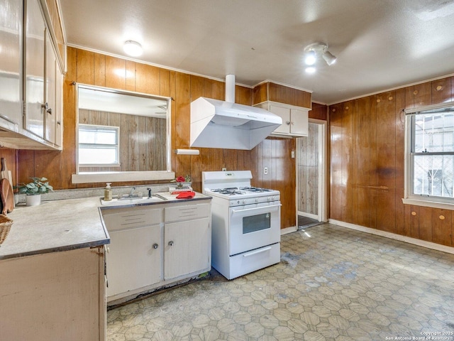 kitchen featuring white cabinetry, sink, a healthy amount of sunlight, white gas stove, and wall chimney exhaust hood