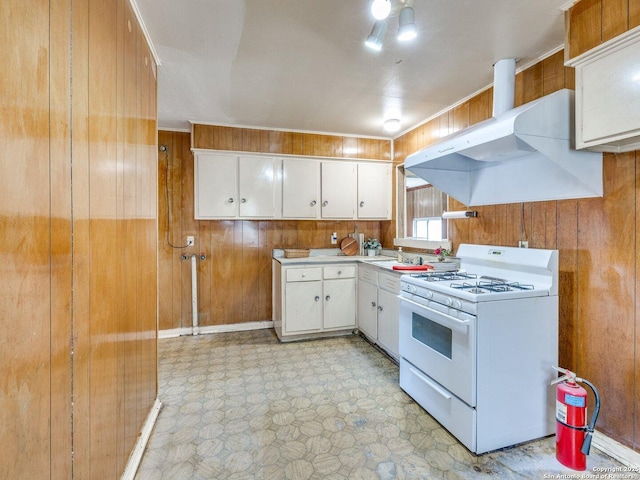 kitchen featuring white cabinetry, sink, wooden walls, and white gas range oven