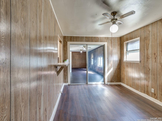 interior space featuring ceiling fan, dark hardwood / wood-style flooring, and wood walls