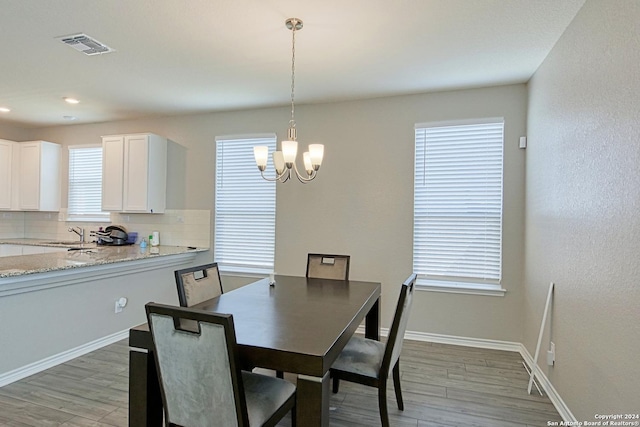 dining room with hardwood / wood-style flooring, sink, and an inviting chandelier