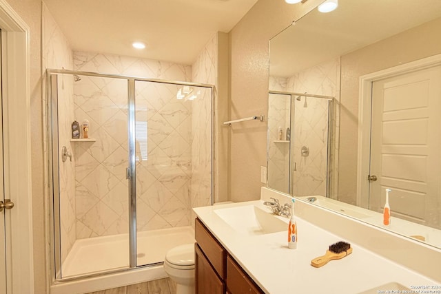 bathroom featuring vanity, an enclosed shower, and toilet