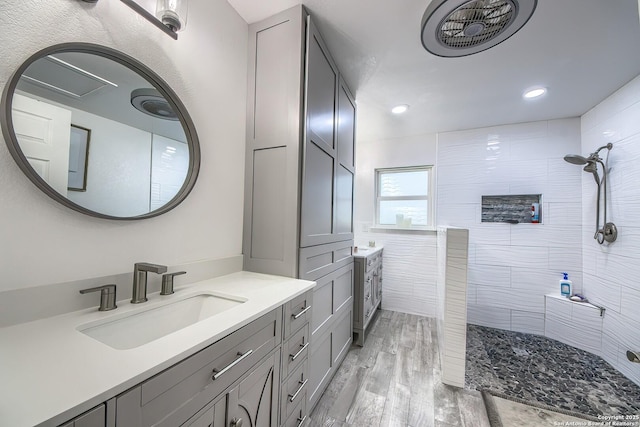 bathroom featuring vanity, wood-type flooring, and a tile shower