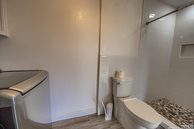 bathroom featuring a tile shower and toilet