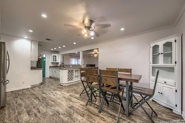 dining space with dark wood-type flooring, ceiling fan, ornamental molding, and sink