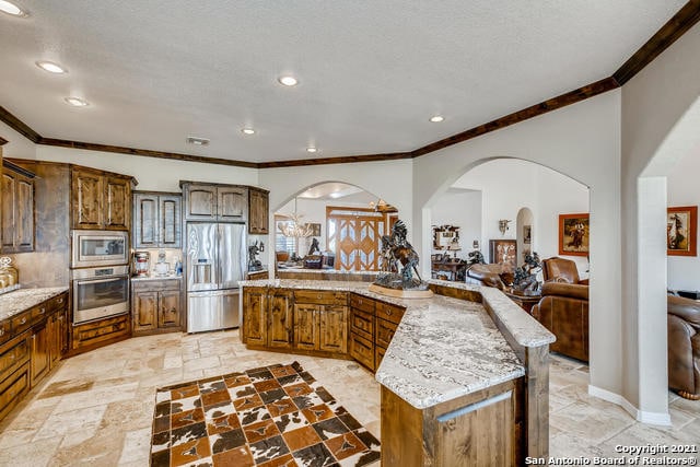 kitchen featuring stainless steel appliances, a kitchen island, light stone counters, and a textured ceiling