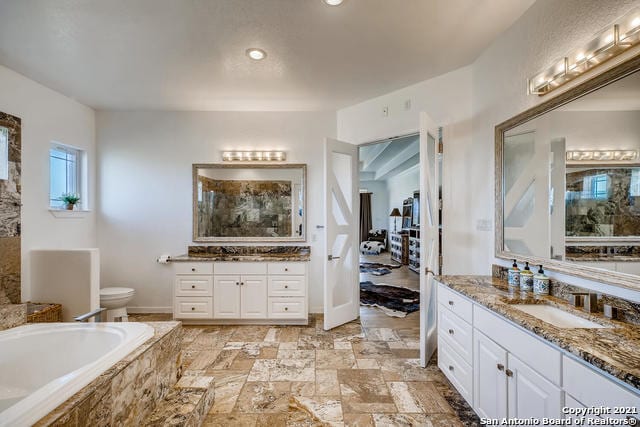 bathroom with vanity and tiled bath