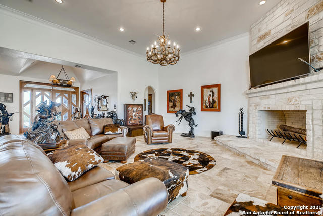 living room featuring ornamental molding, a stone fireplace, and a chandelier