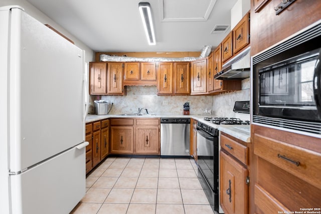 kitchen featuring dishwasher, black range with gas stovetop, backsplash, white fridge, and light tile patterned floors