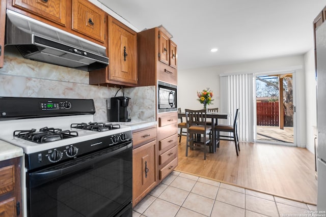 kitchen featuring tasteful backsplash, range with gas cooktop, black microwave, and light tile patterned flooring