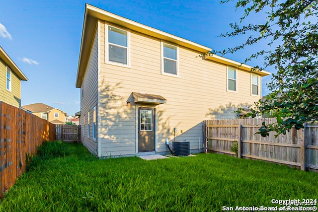 rear view of property with a yard and central AC unit