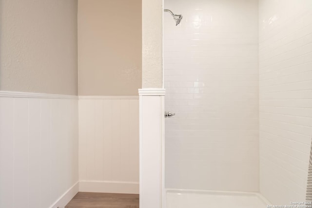 bathroom with hardwood / wood-style flooring and a tile shower