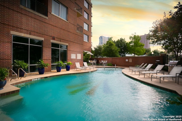 pool at dusk with a patio area