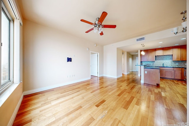 kitchen with decorative light fixtures, tasteful backsplash, a center island, ceiling fan, and light hardwood / wood-style flooring