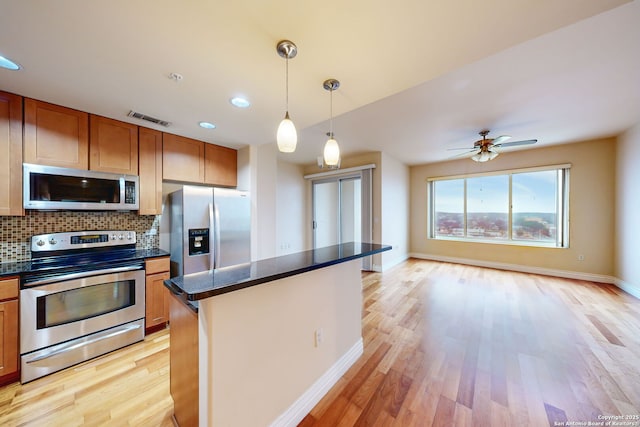 kitchen featuring tasteful backsplash, a center island, hanging light fixtures, stainless steel appliances, and light hardwood / wood-style floors