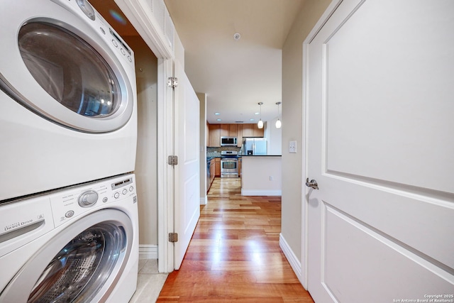 clothes washing area with stacked washing maching and dryer and light hardwood / wood-style flooring