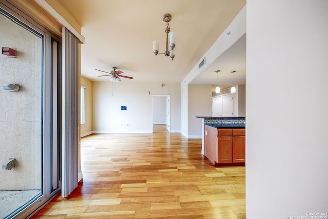 interior space featuring pendant lighting, backsplash, ceiling fan with notable chandelier, and light wood-type flooring