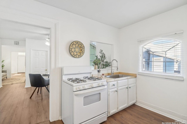 kitchen featuring dark hardwood / wood-style floors, sink, white cabinets, ceiling fan, and white gas stove