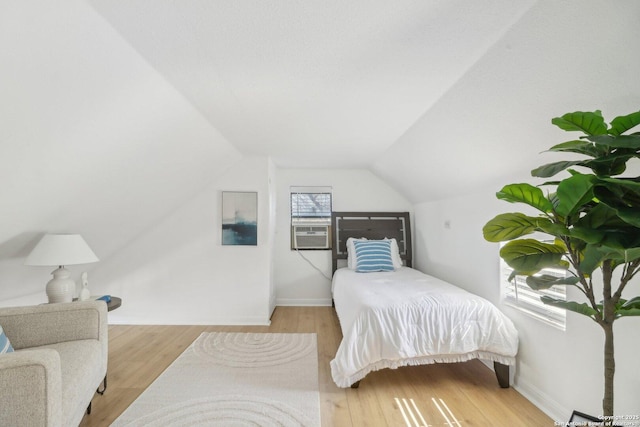 bedroom featuring lofted ceiling, cooling unit, and light hardwood / wood-style flooring