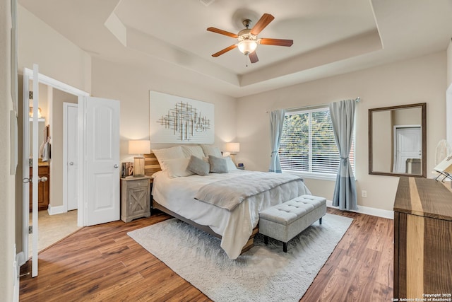 bedroom featuring hardwood / wood-style flooring, ceiling fan, and a tray ceiling