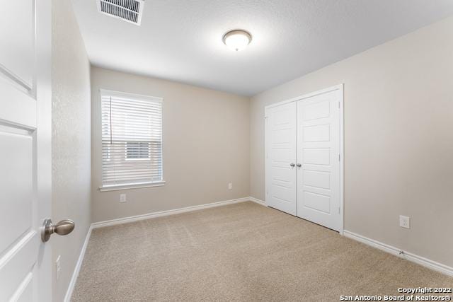 unfurnished bedroom featuring light colored carpet and a closet