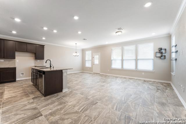 kitchen with sink, light stone counters, crown molding, dark brown cabinets, and dishwasher