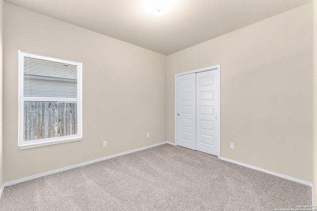 unfurnished bedroom featuring light colored carpet and a closet