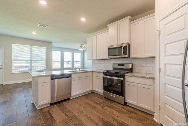 kitchen featuring sink, stainless steel appliances, white cabinets, decorative backsplash, and kitchen peninsula