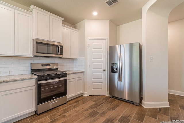 kitchen with white cabinetry, light stone countertops, tasteful backsplash, and stainless steel appliances