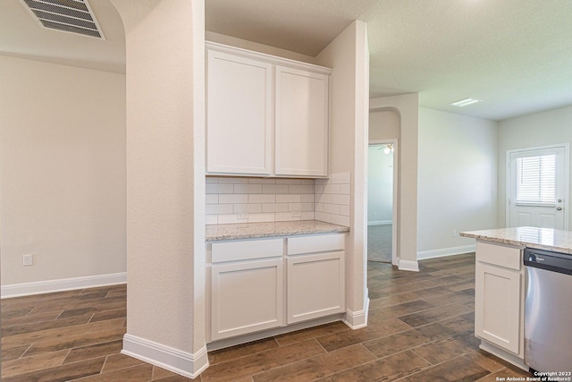 kitchen featuring white cabinetry, light stone countertops, dishwasher, and backsplash