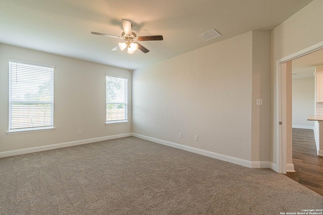 spare room featuring ceiling fan and dark colored carpet