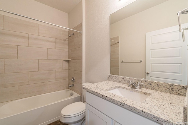 full bathroom featuring tiled shower / bath, vanity, and toilet