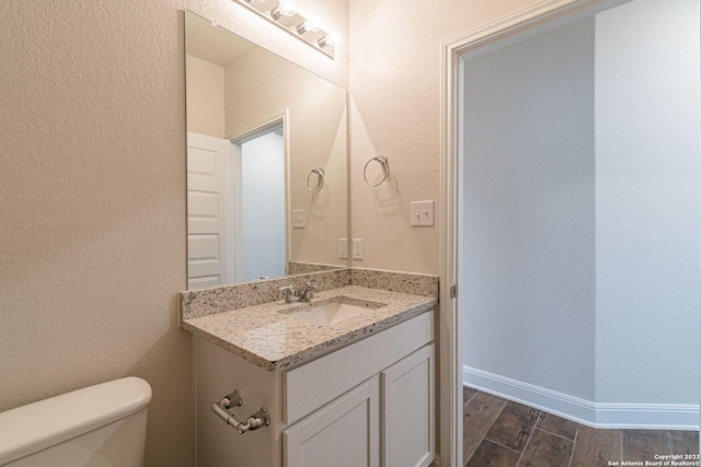 bathroom with wood-type flooring, vanity, and toilet