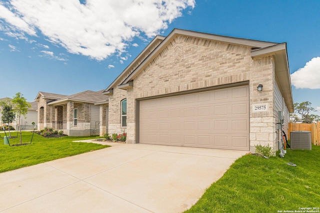 view of front of home with a garage, central AC unit, and a front lawn