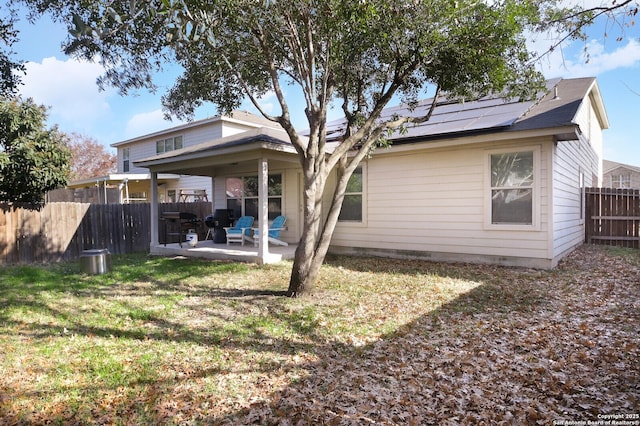 back of property with a lawn, a patio, and solar panels