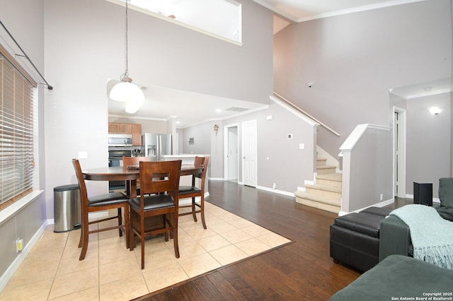 dining space with a high ceiling, crown molding, and light hardwood / wood-style flooring