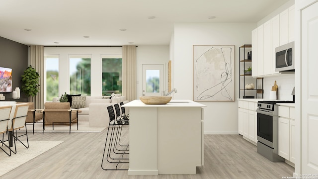 kitchen with white cabinetry, appliances with stainless steel finishes, a kitchen island, and light hardwood / wood-style flooring