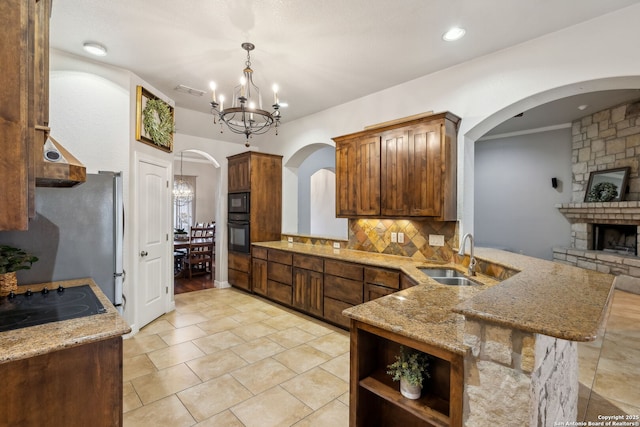 kitchen featuring sink, kitchen peninsula, a notable chandelier, pendant lighting, and backsplash