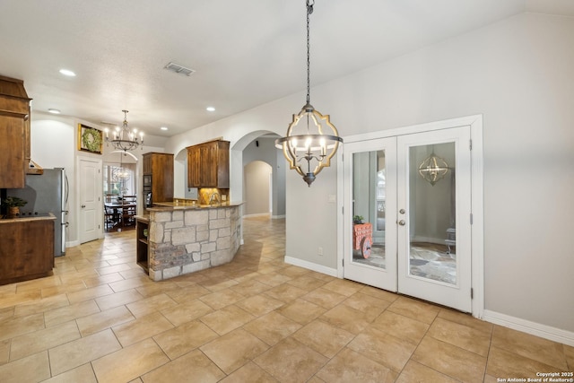 kitchen with kitchen peninsula, stainless steel fridge, a chandelier, and decorative light fixtures