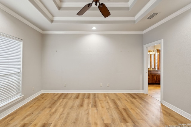 empty room featuring crown molding, a raised ceiling, ceiling fan, and light wood-type flooring