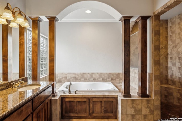 bathroom featuring tiled tub, crown molding, vanity, and ornate columns