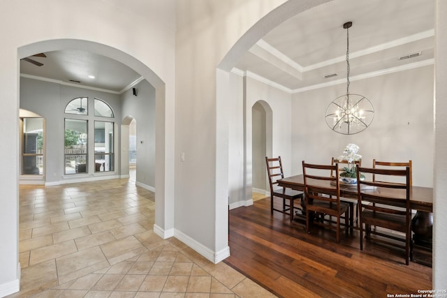 tiled dining area with an inviting chandelier, crown molding, and a raised ceiling