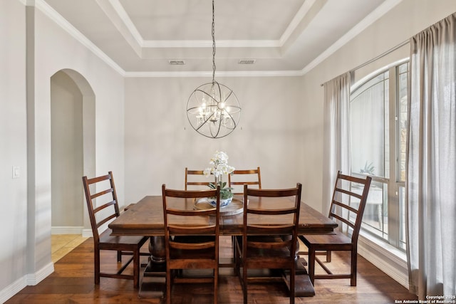 dining space with a notable chandelier, dark hardwood / wood-style floors, a raised ceiling, and a wealth of natural light