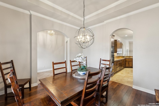 dining room with ornamental molding, a raised ceiling, light hardwood / wood-style flooring, and a notable chandelier