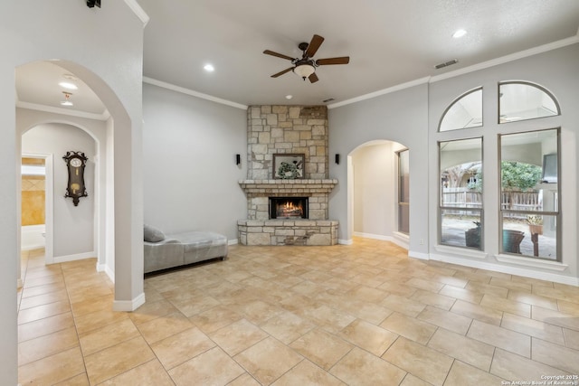 tiled living room with crown molding, a stone fireplace, and ceiling fan