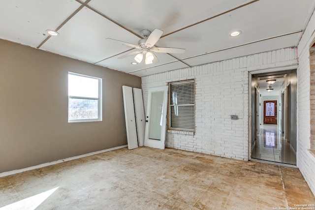 spare room featuring ceiling fan and brick wall