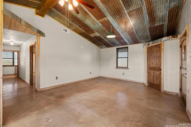 spare room featuring lofted ceiling with beams, a healthy amount of sunlight, concrete floors, and ceiling fan